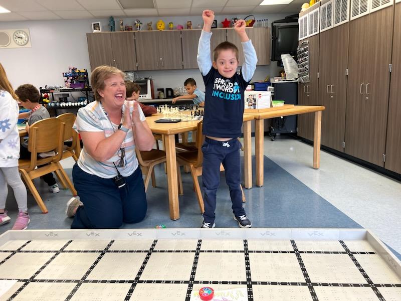 student celebrating coding a robot